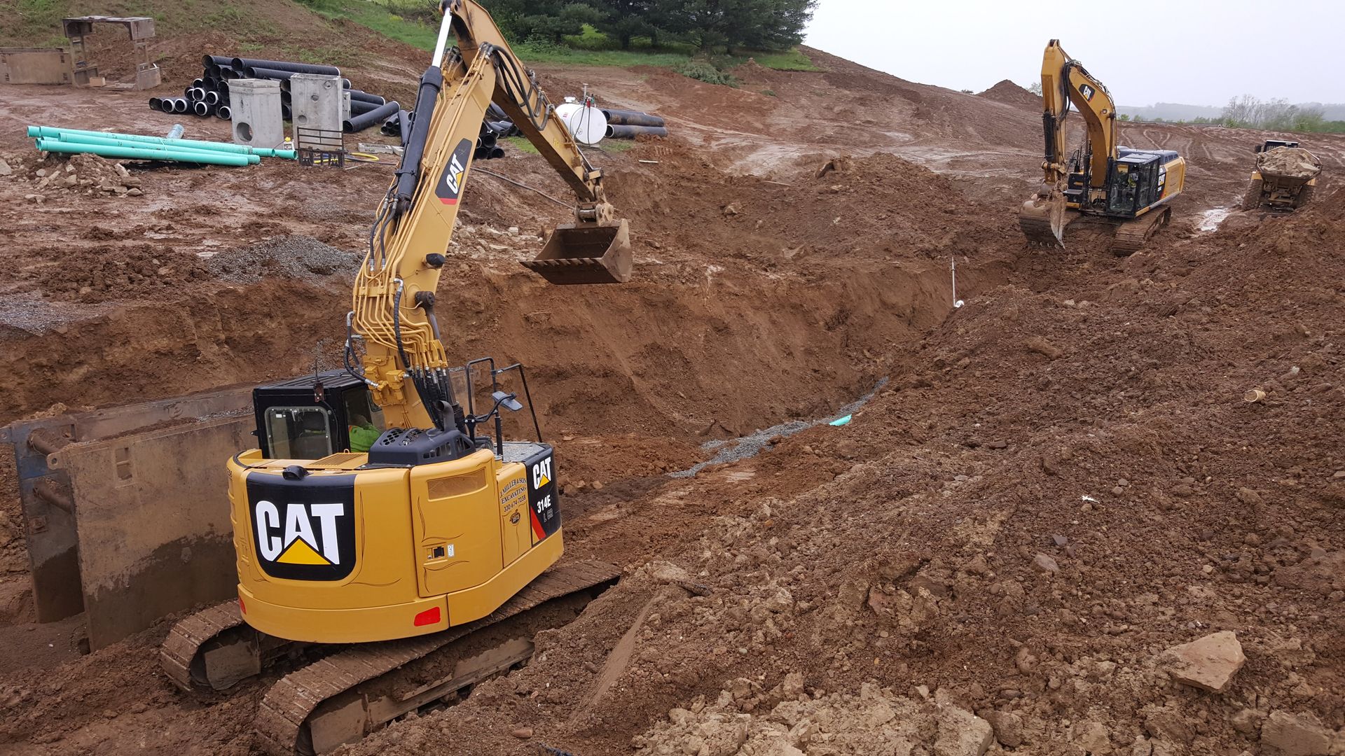 Two yellow excavators digging in muddy ground.