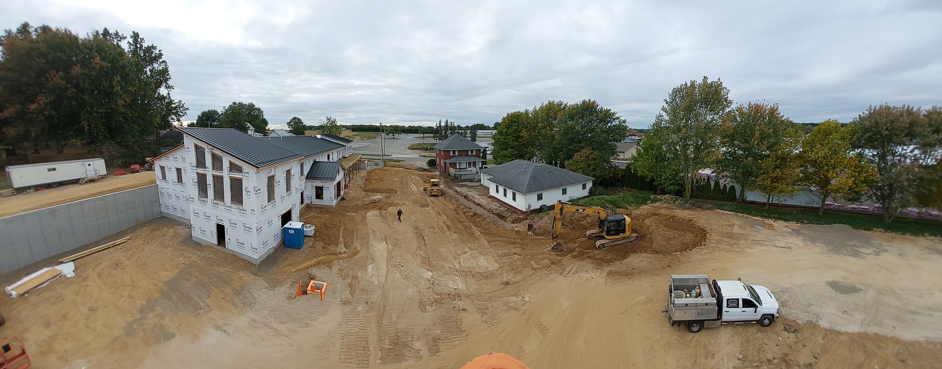 Construction site with unfinished houses and a white truck on a cloudy day.