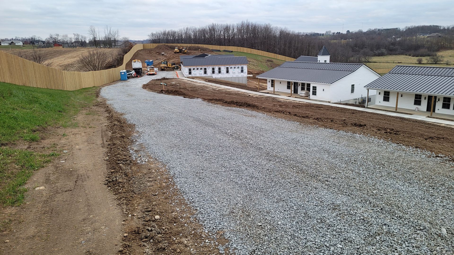 Construction site with gravel pathway, partially built houses, and heavy machinery.