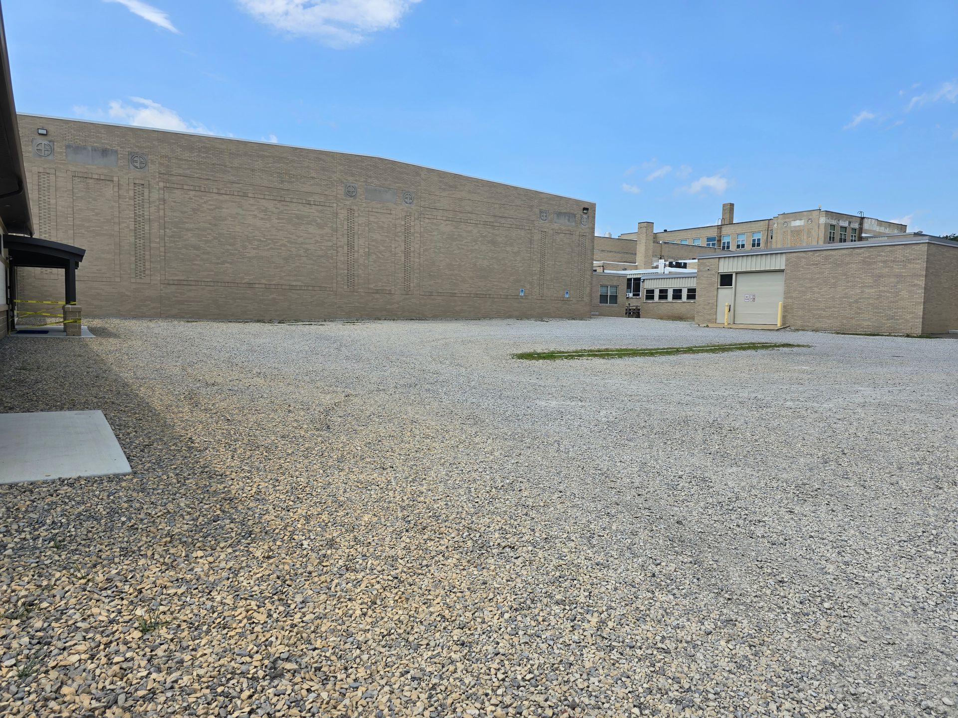Gravel-covered flat rooftop with brick walls under a partly cloudy sky.