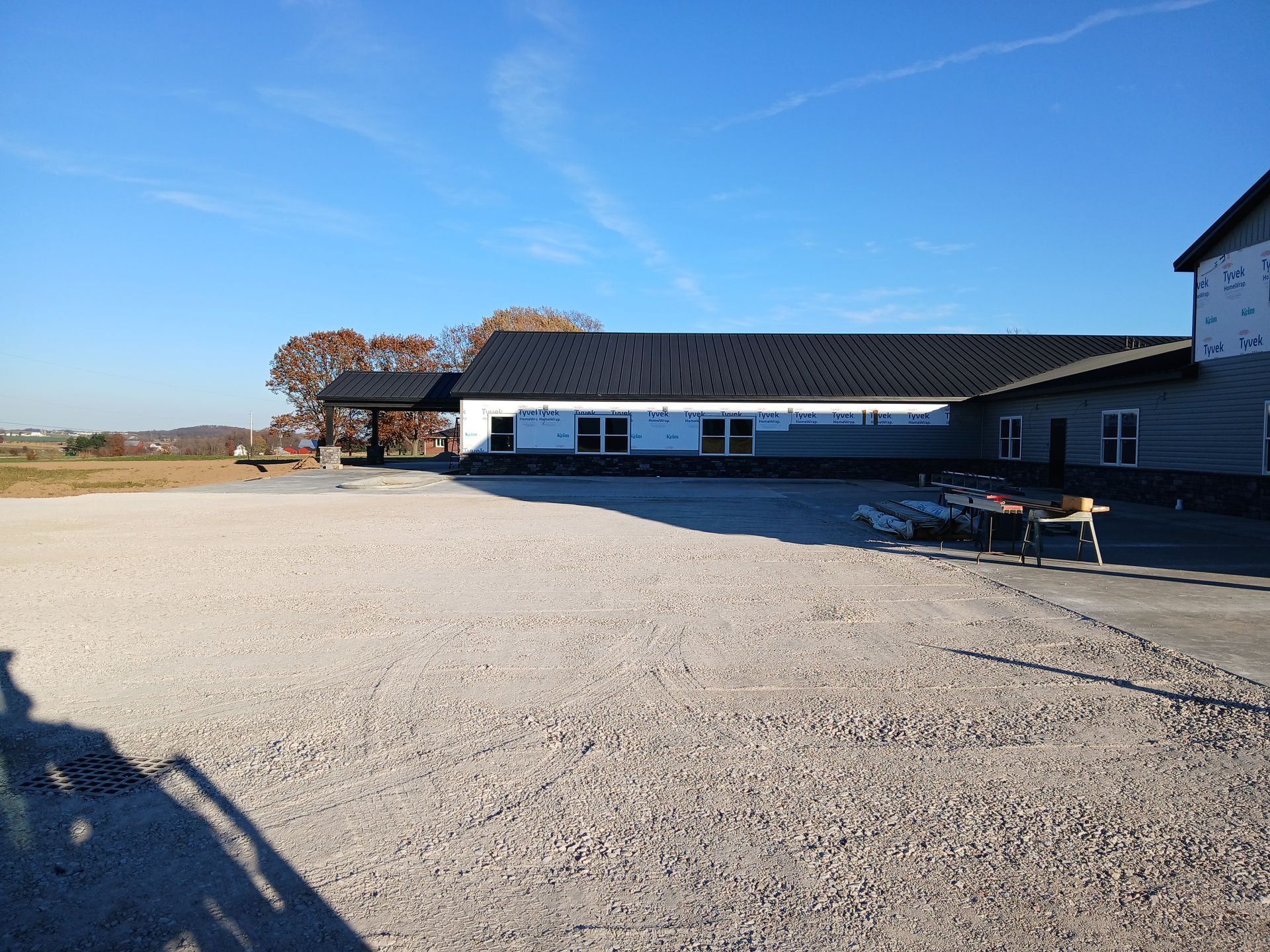 A gravel-covered outdoor area with a building. Clear blue sky.