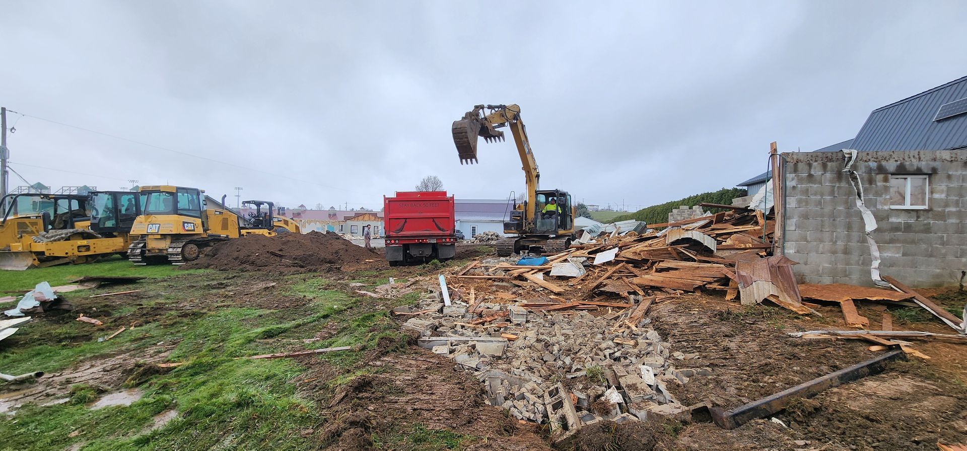 Construction site with excavator and other heavy machinery; cloudy day.
