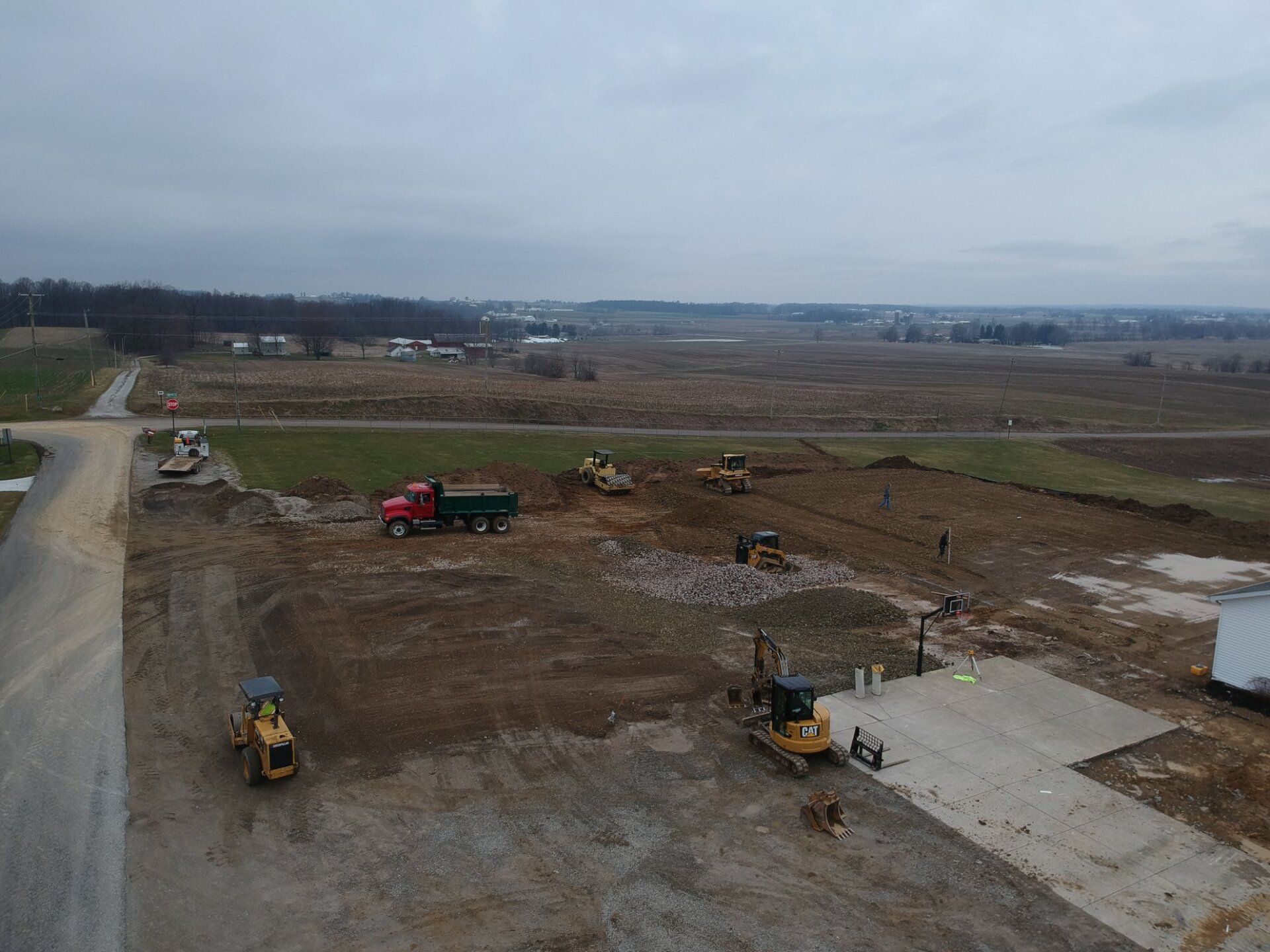 Construction site with heavy machinery, including trucks and excavators, clearing land for development on a cloudy day.