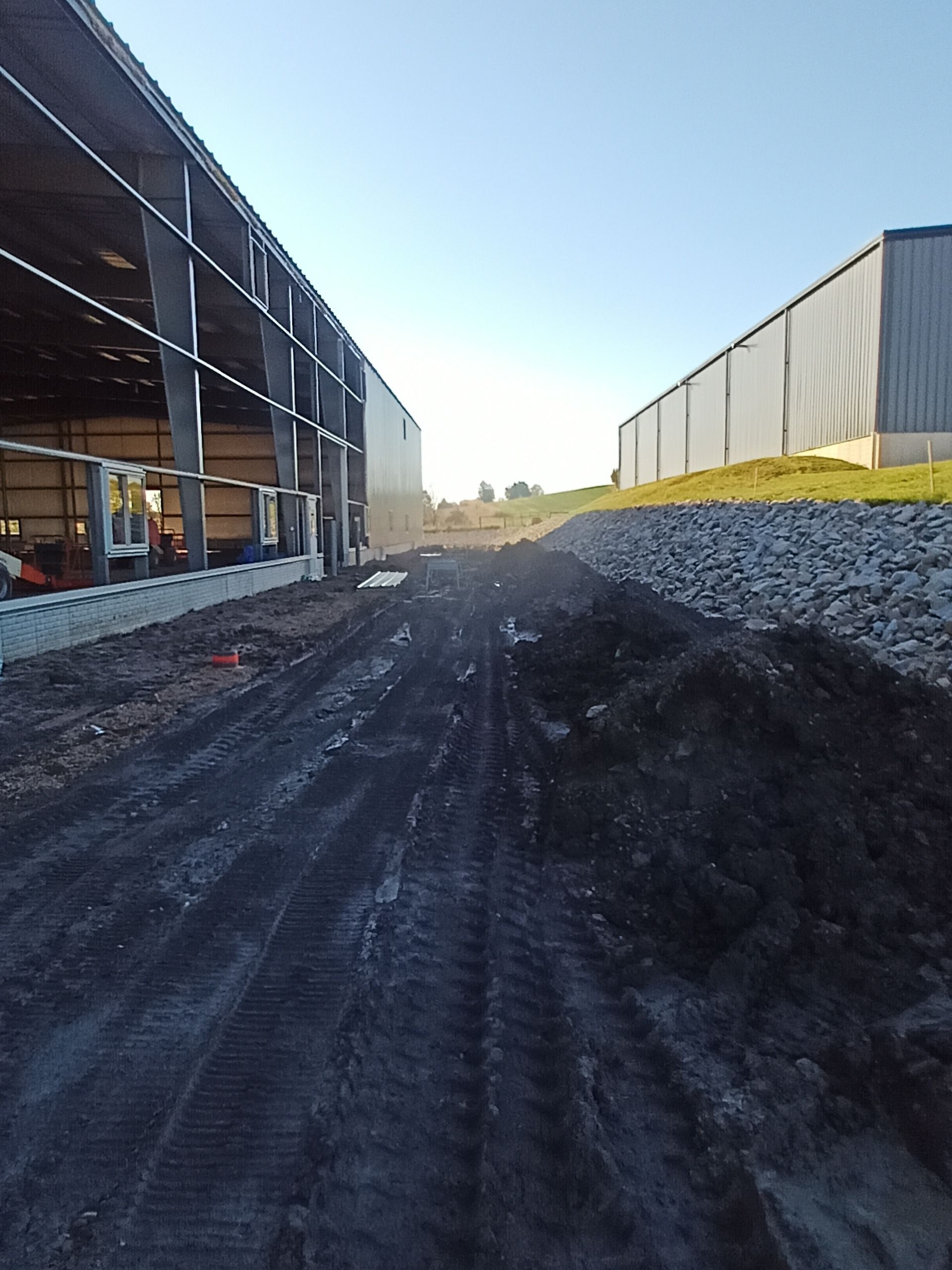 Construction site with dirt path between unfinished buildings under a clear sky.