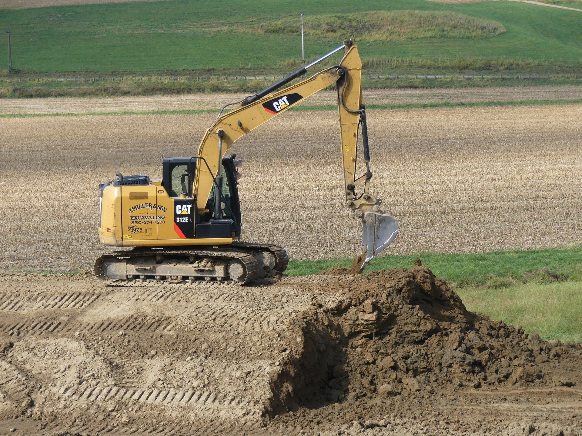 Yellow Caterpillar excavator digging in a field.