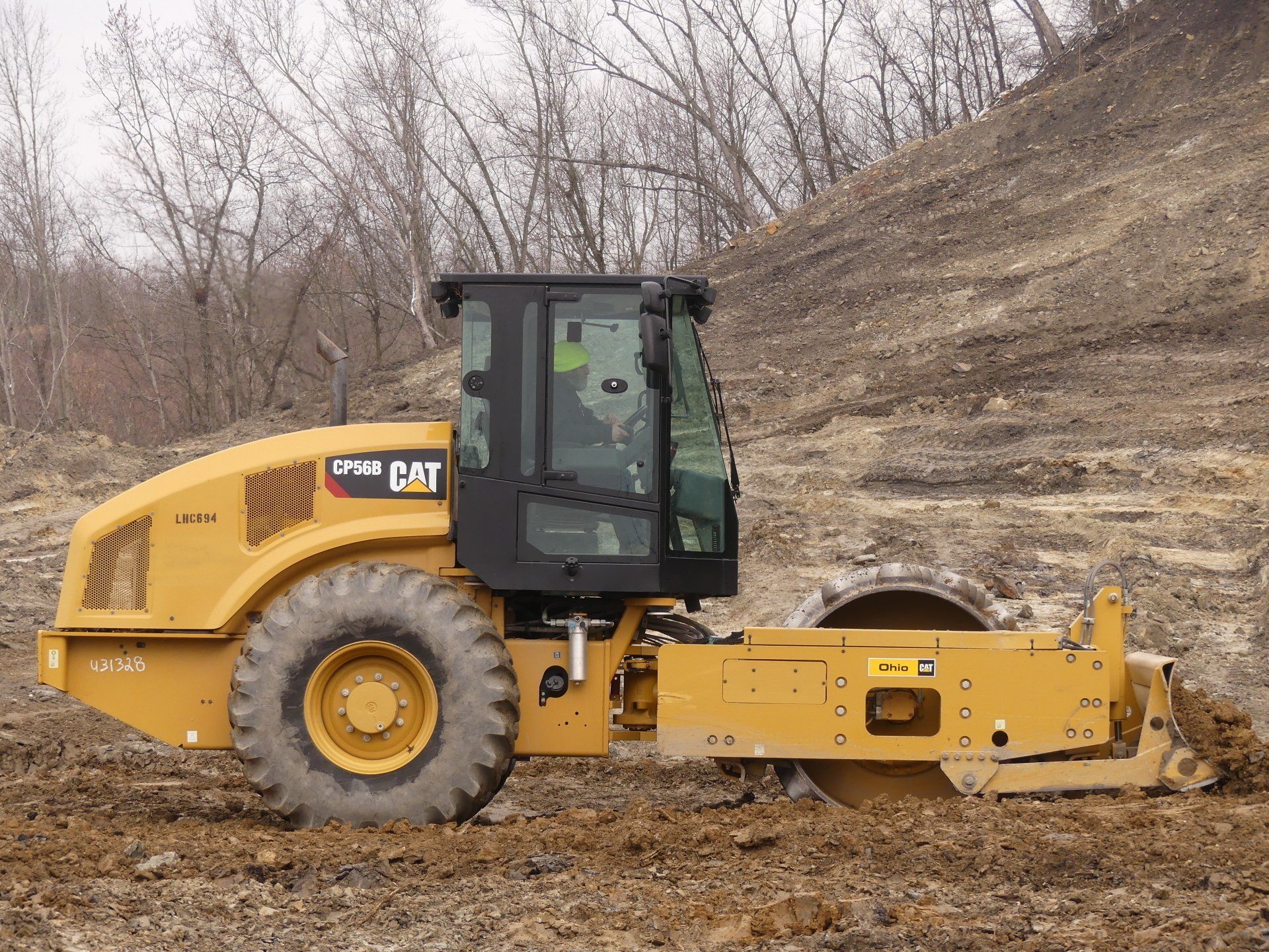 Yellow Caterpillar soil compactor on a construction site, compacting soil.