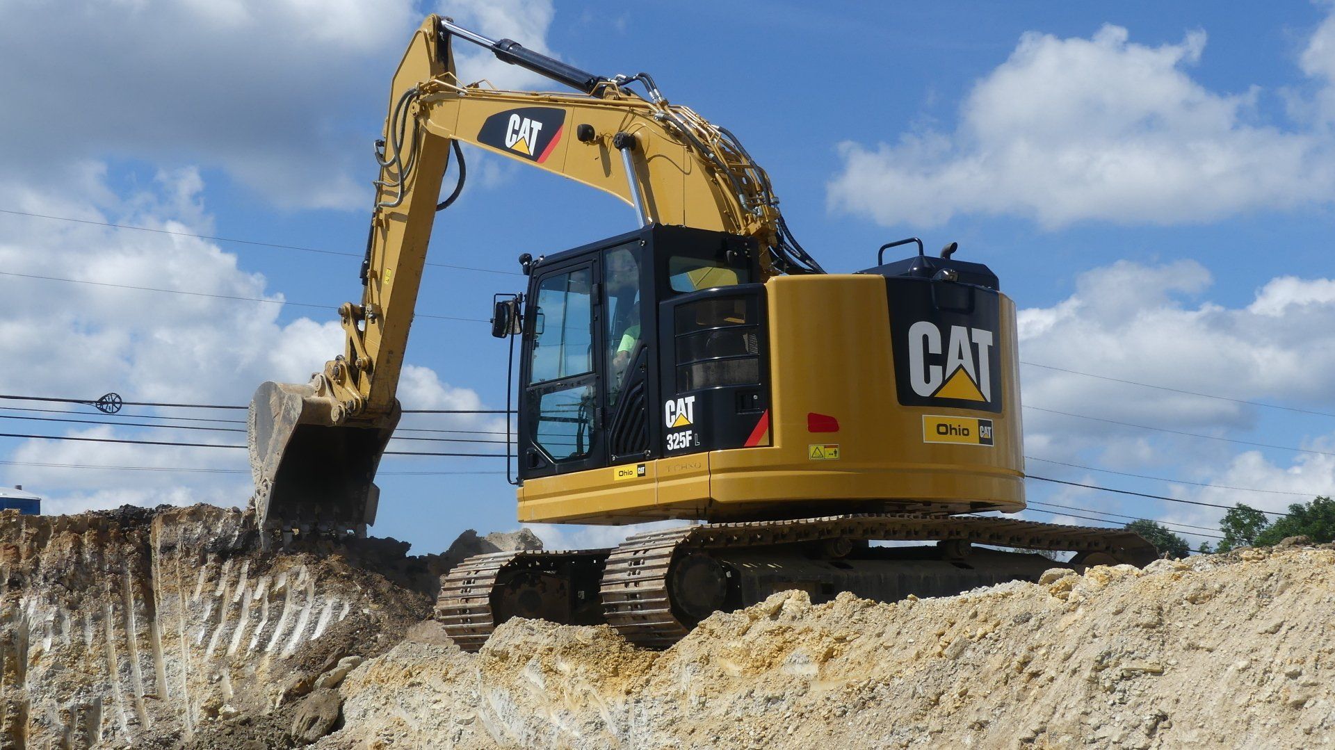 Yellow Caterpillar excavator digging earth on a sunny day.