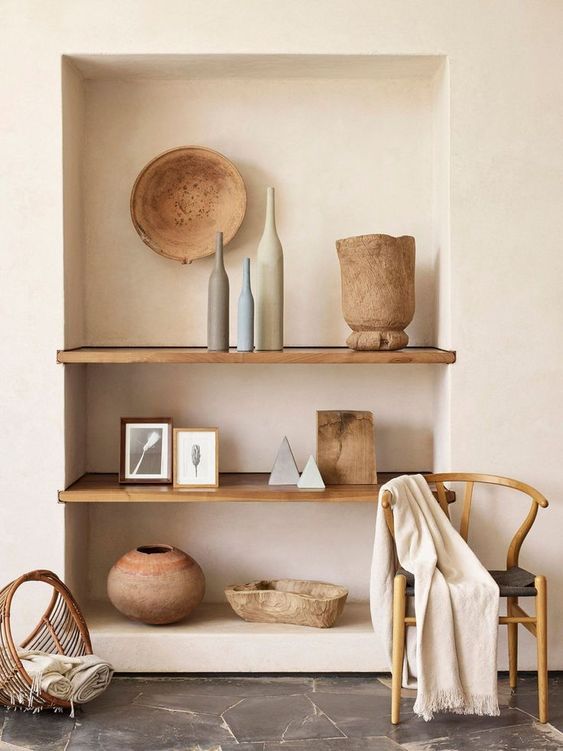 A living room with a shelf filled with vases and bowls