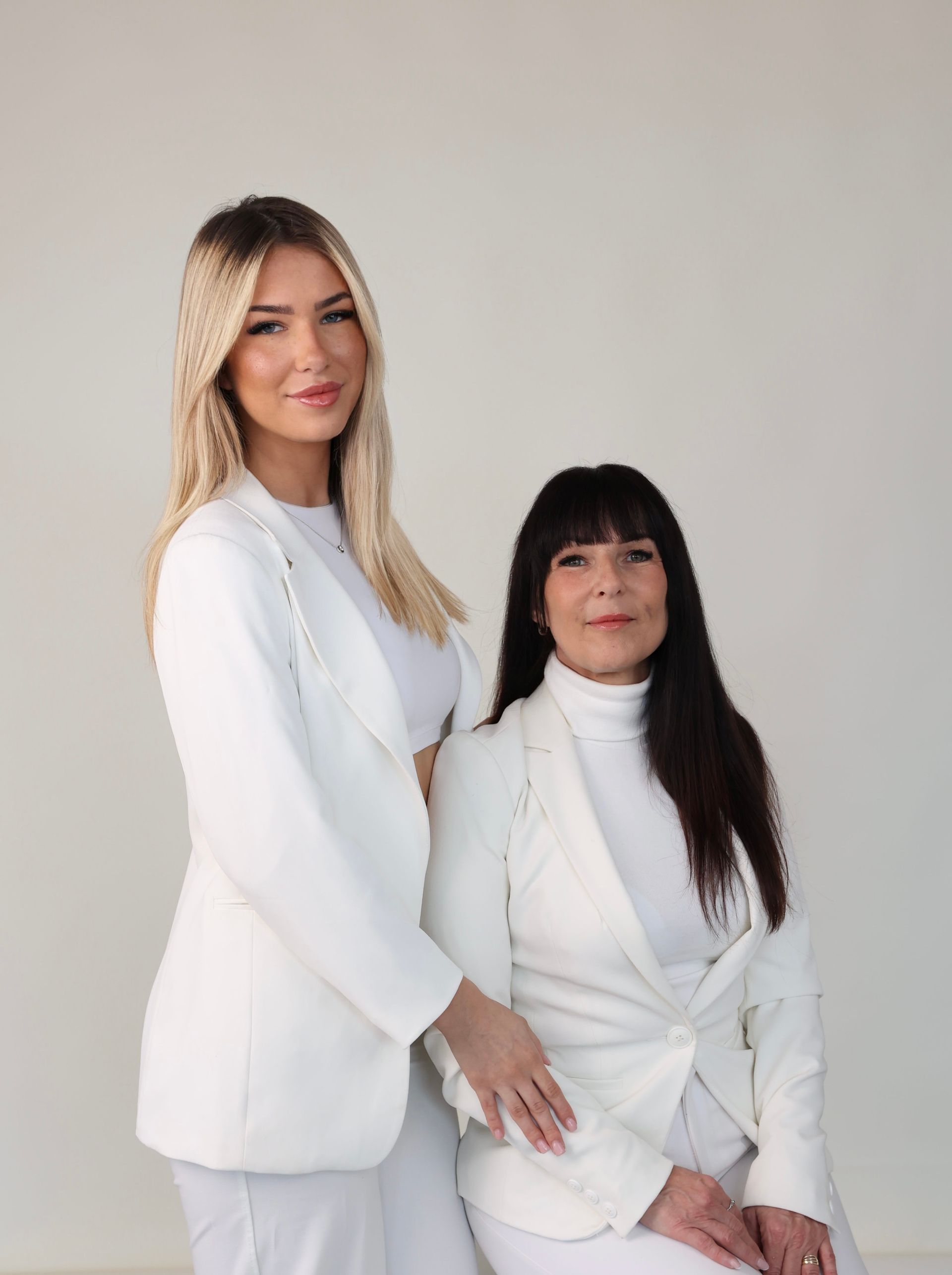 Two women in white suits are posing for a picture.