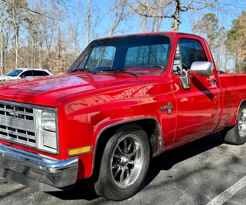 A bright red Chevrolet C/K pickup truck parked in an outdoor lot on a sunny day.