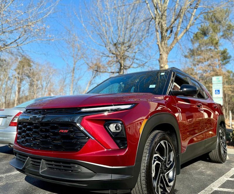 A red Chevrolet Blazer RS SUV parked in a lot under a clear blue sky, viewed from a low angle.