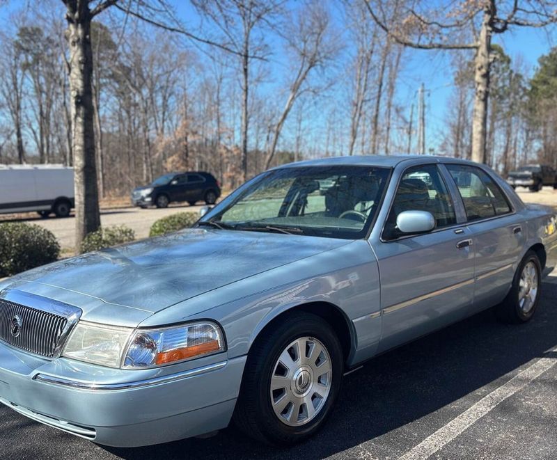 A light blue Mercury Grand Marquis sedan parked in an outdoor lot on a sunny day.