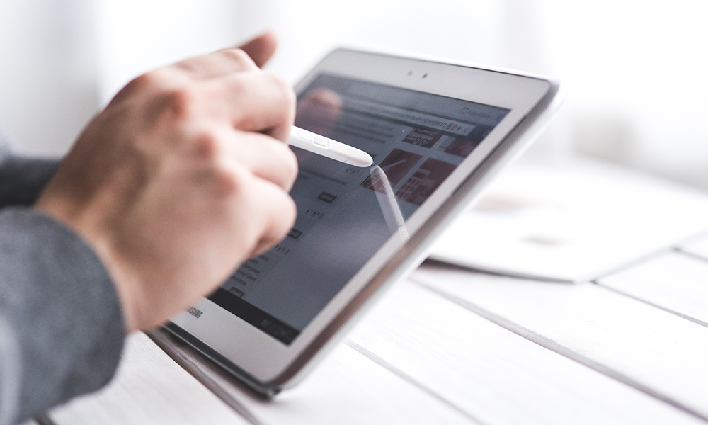 A person is writing on a tablet with a pen.