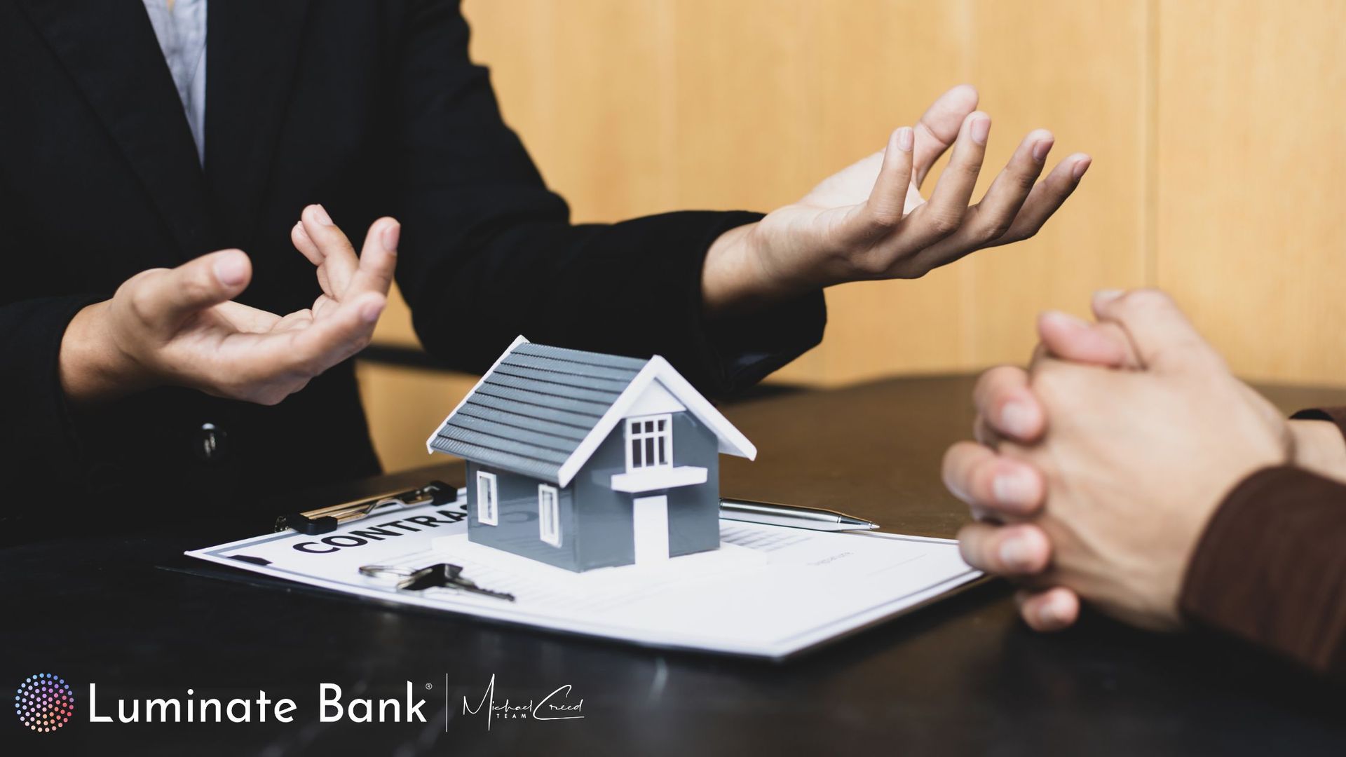 Real estate agent gesturing to client, with model house on documents.