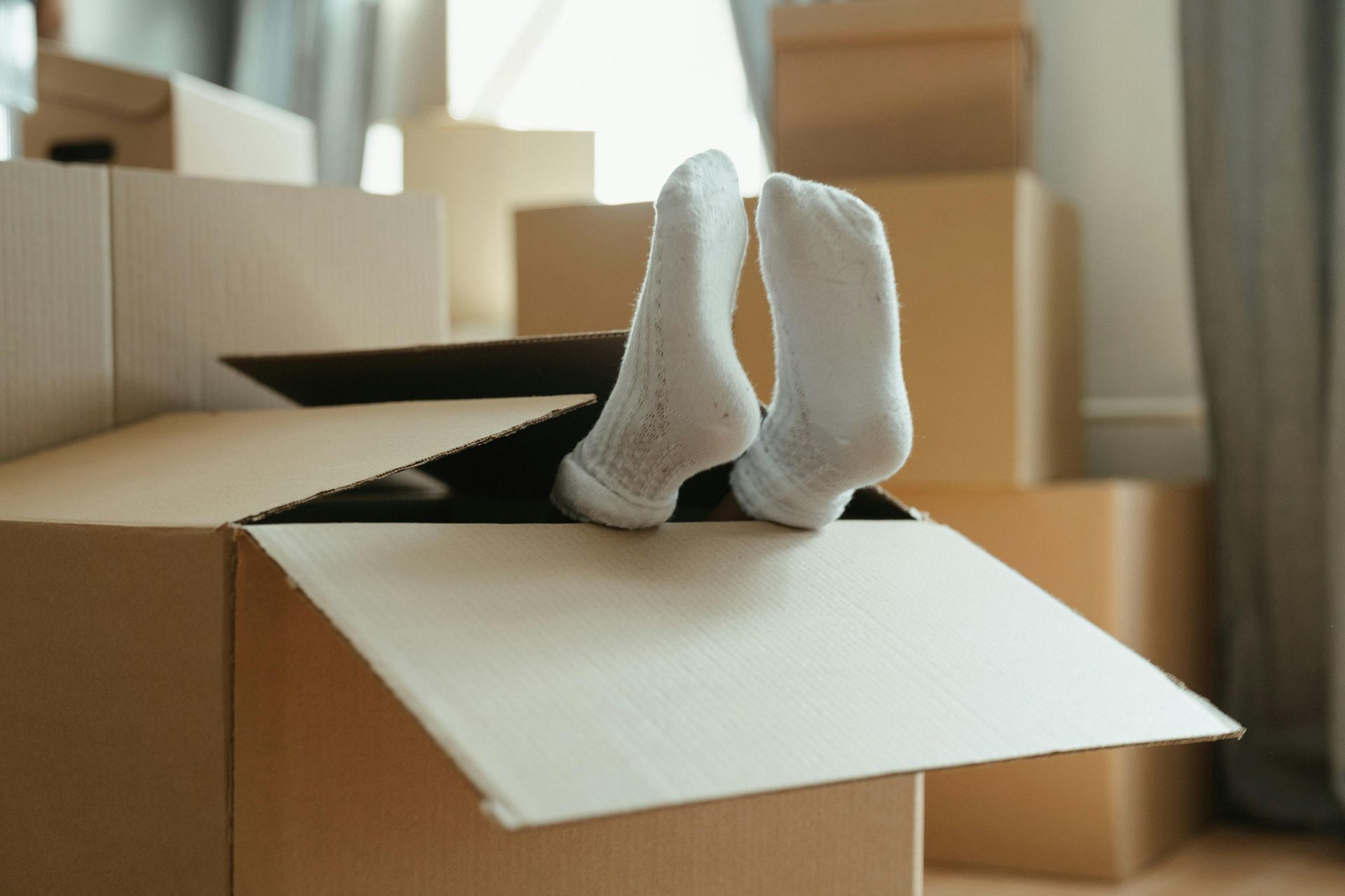 Feet with sock on them outside a moving box; having fun while moving. 