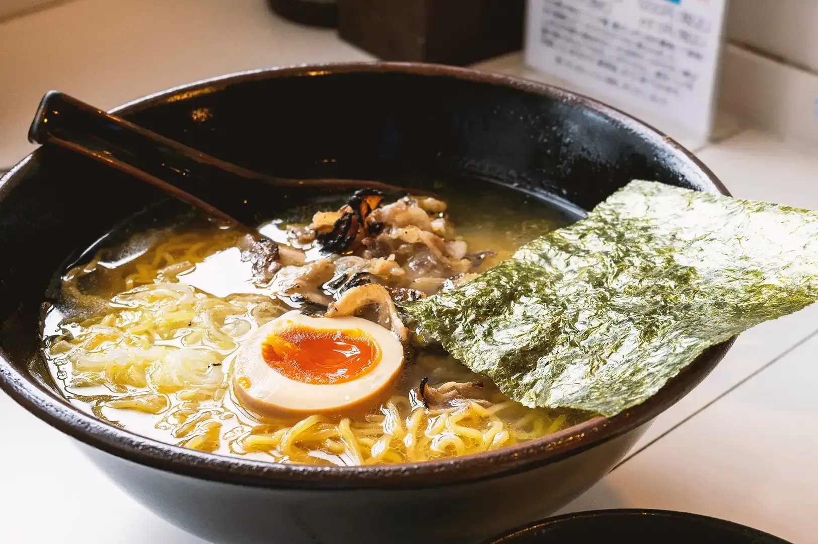 Ramen noodles in rich broth with egg, seaweed and mushrooms served in a glossy black bowl
