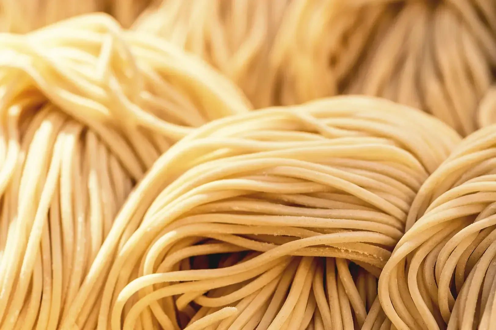 Strings of raw uncooked noodles slightly dusted of flour