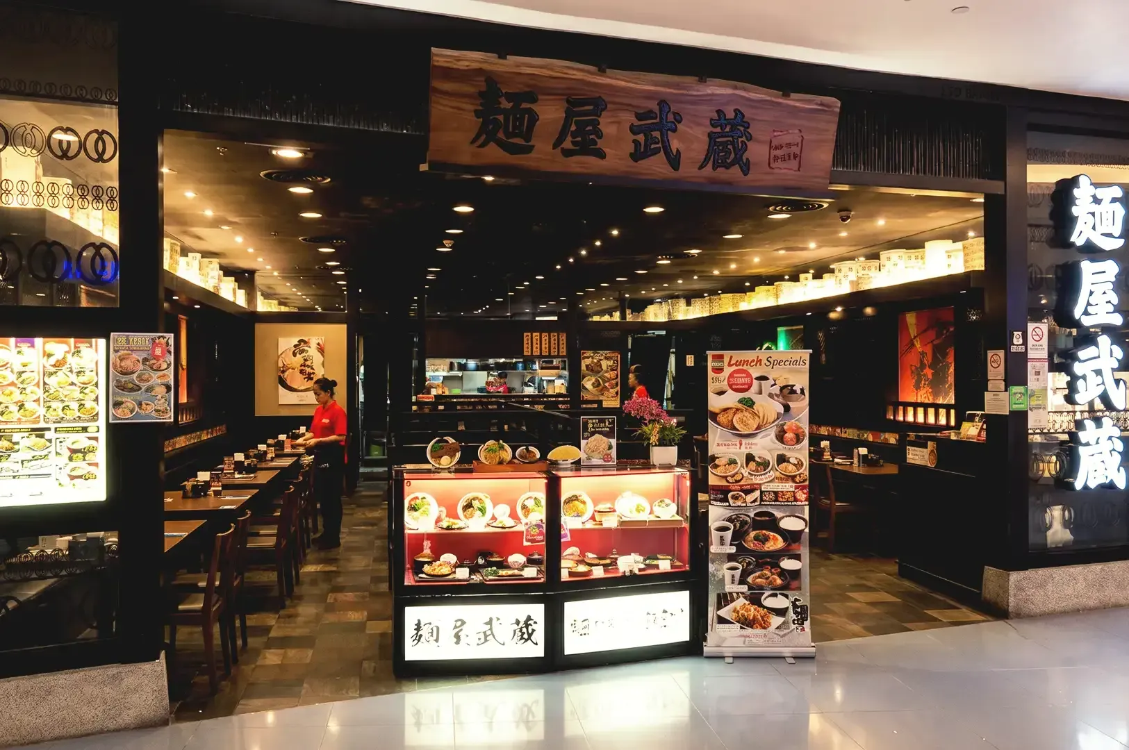 Japanese themed storefront of Menya Musashi with dark wood accents and displayed ramen menu boards