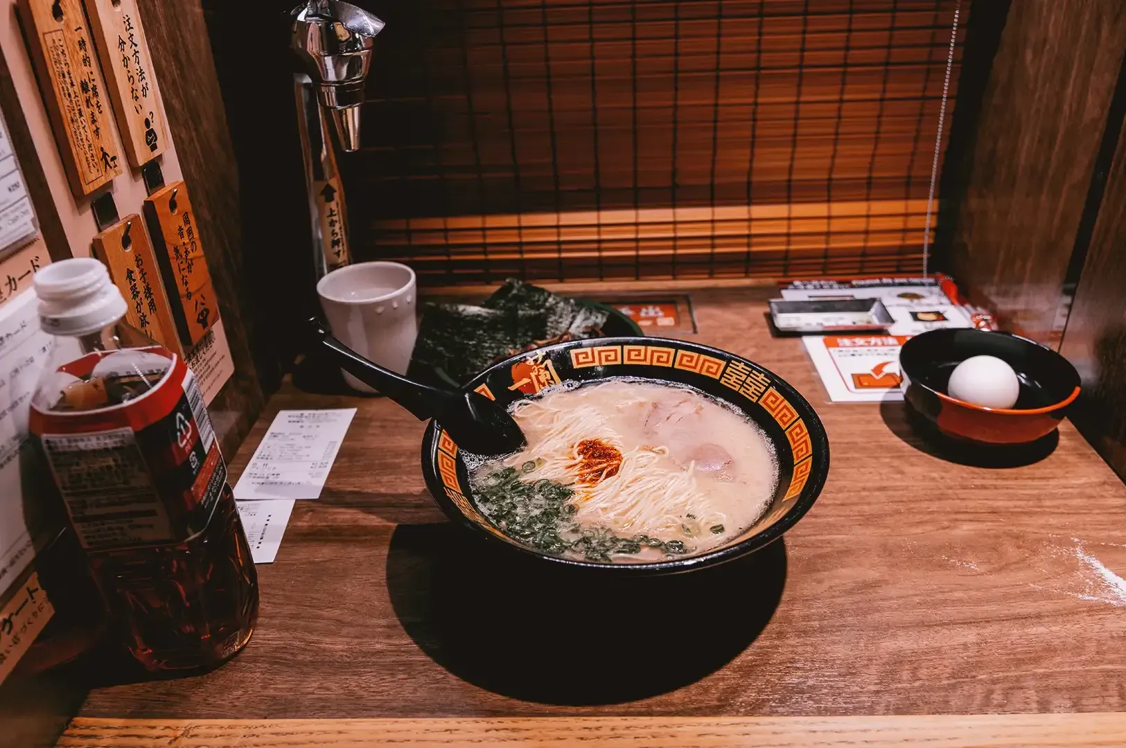 Creamy ramen composed of noodles, seaweed, chili oil and pork slices in a black traditional japanese
