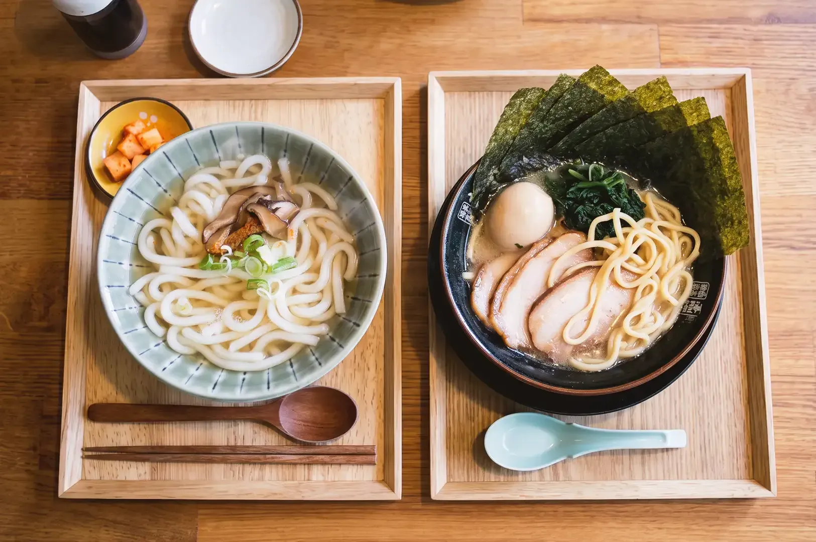 Side by side serving of udon noodles on the left and ramen noodles on the right