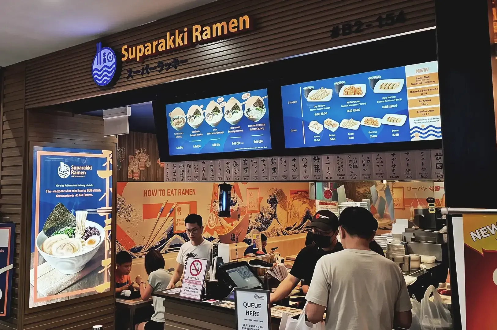 Suparakki Ramen storefront with LED screen displayed menu and peek of interior occupied by customers