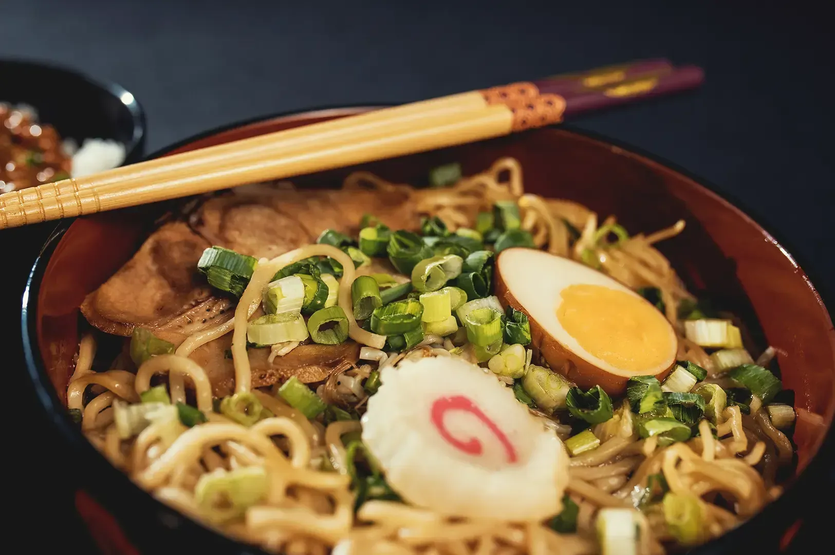 A bowl of Japanese ramen topped with spring onions, meat and egg