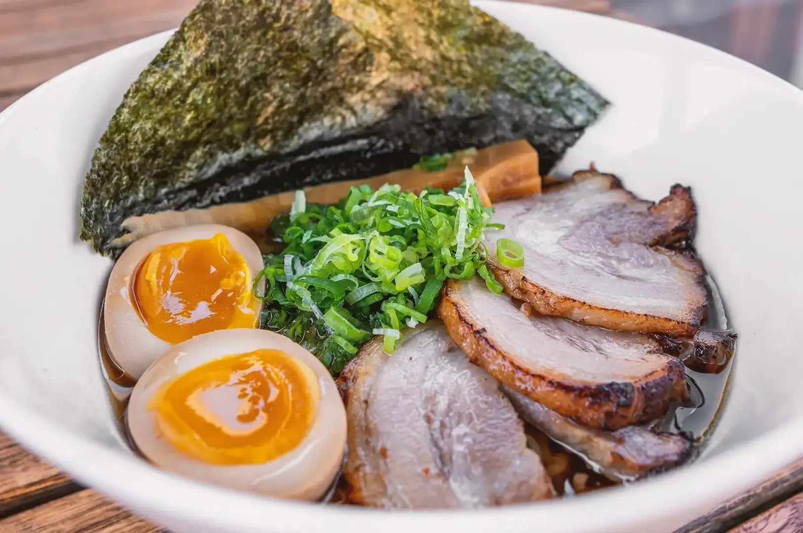 Close up of tonkotsu ramen made of sliced chashu pork, sliced egg, seaweed, ramen noodles and broth