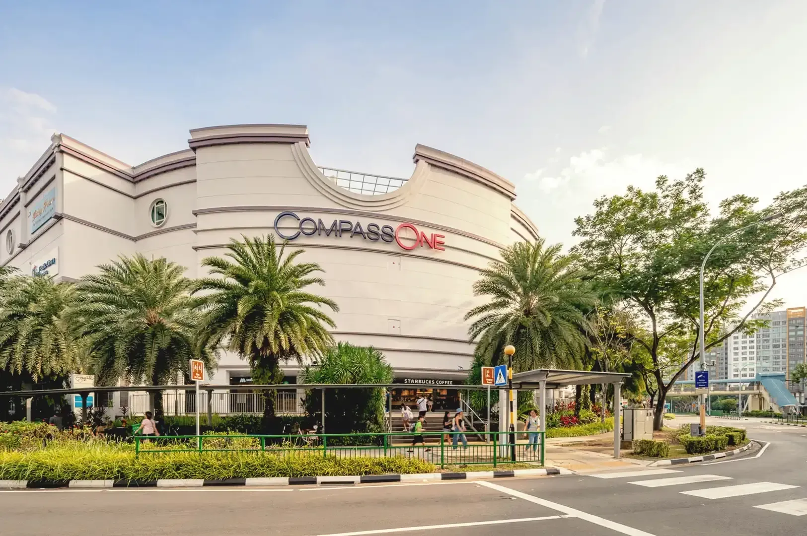 Clea blue sky daylight photo of Compass One mall surrounded by palm trees