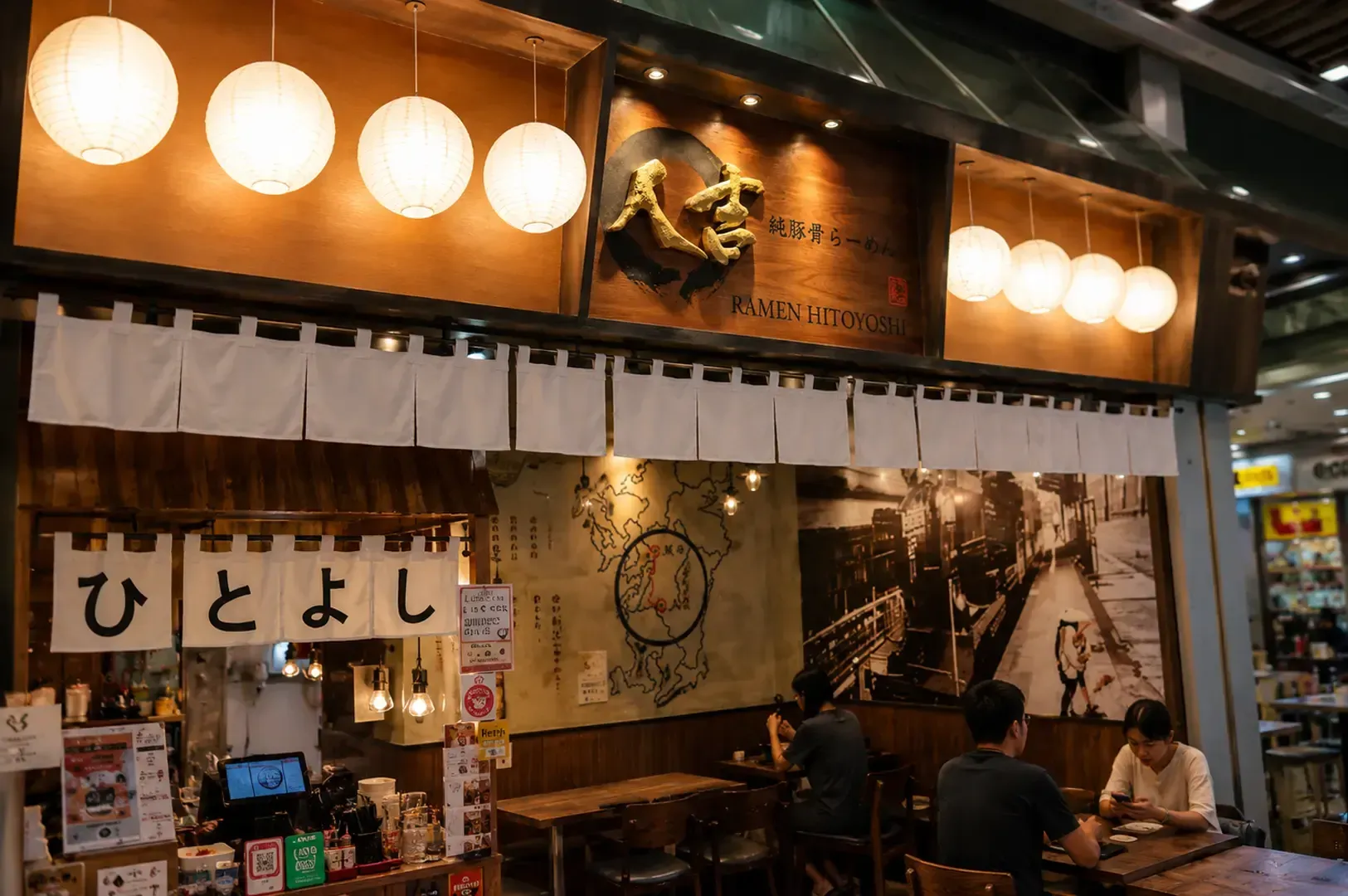 Hitoyoshi restaurant storefront with traditional Japanese paper lanterns, noren curtains, and customers dining at wooden tables