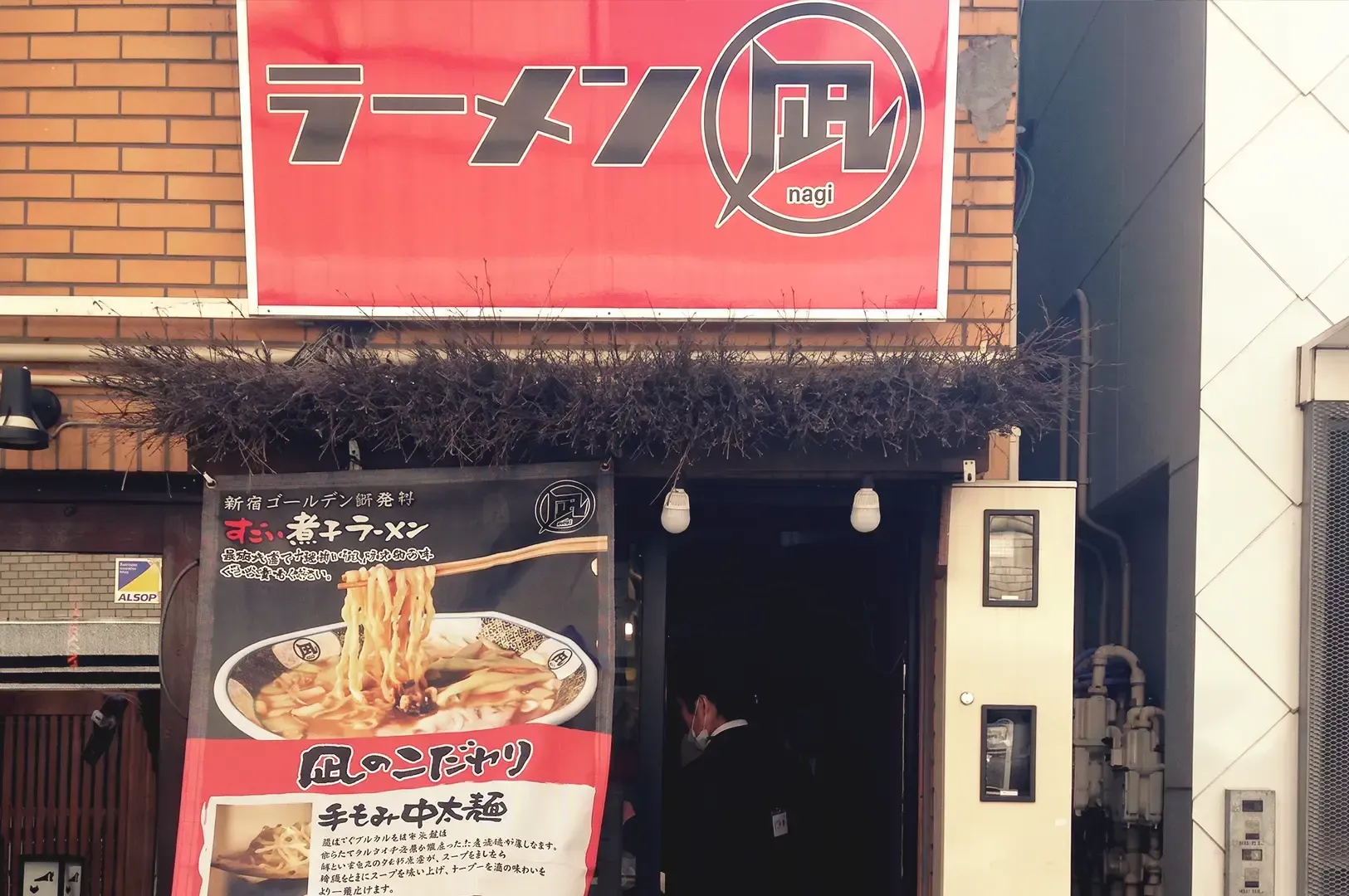 Large red signage of Nagi with displayed ramen poster infront