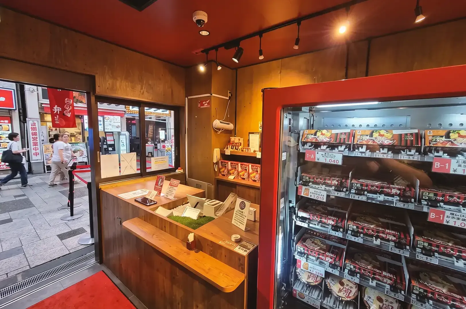 Counter of Ichiran Ramen Dotonbori right off the entrace and a red vending machine in warm ambient lighting