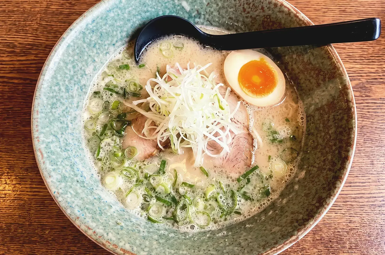 Top view of creamy ramen dish seasoned with vegetables and egg topping