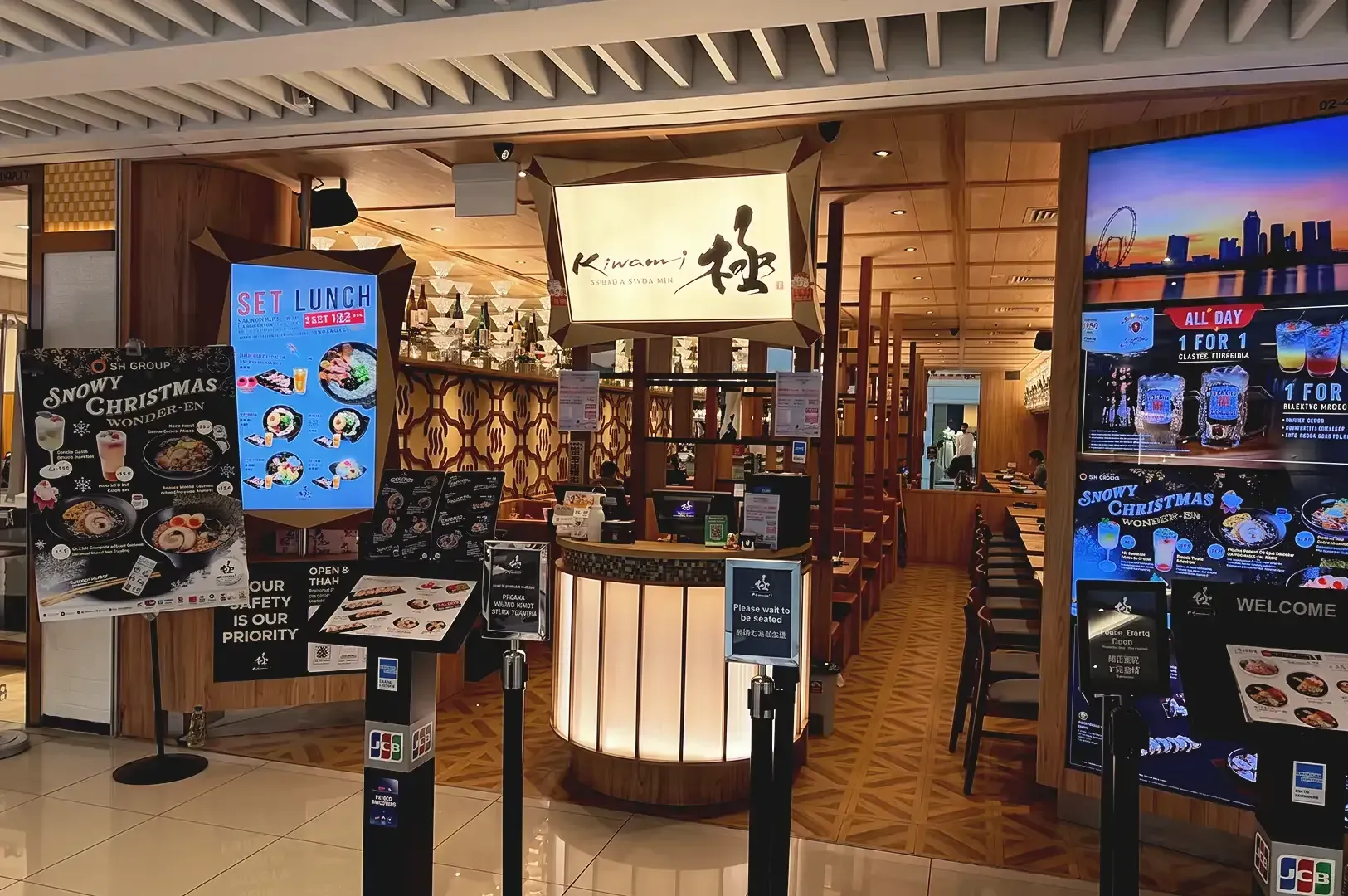 Busy storefront of Kiwami with menu posters, LED screens and visible japanese inspired interior dining area