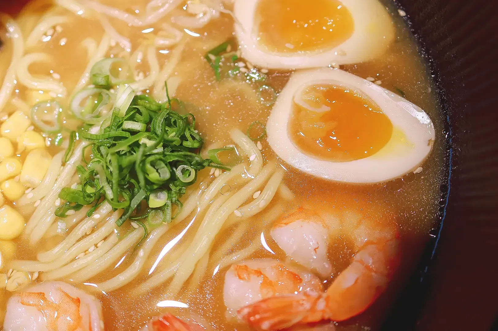 Freshly cooked ramen broth with spring onions, corn, egg and shrimp
