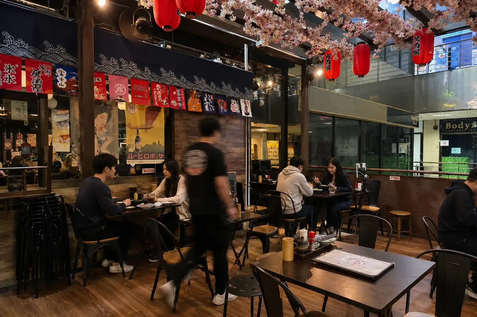 Restaurant interior with diners under cherry blossoms and red lanterns