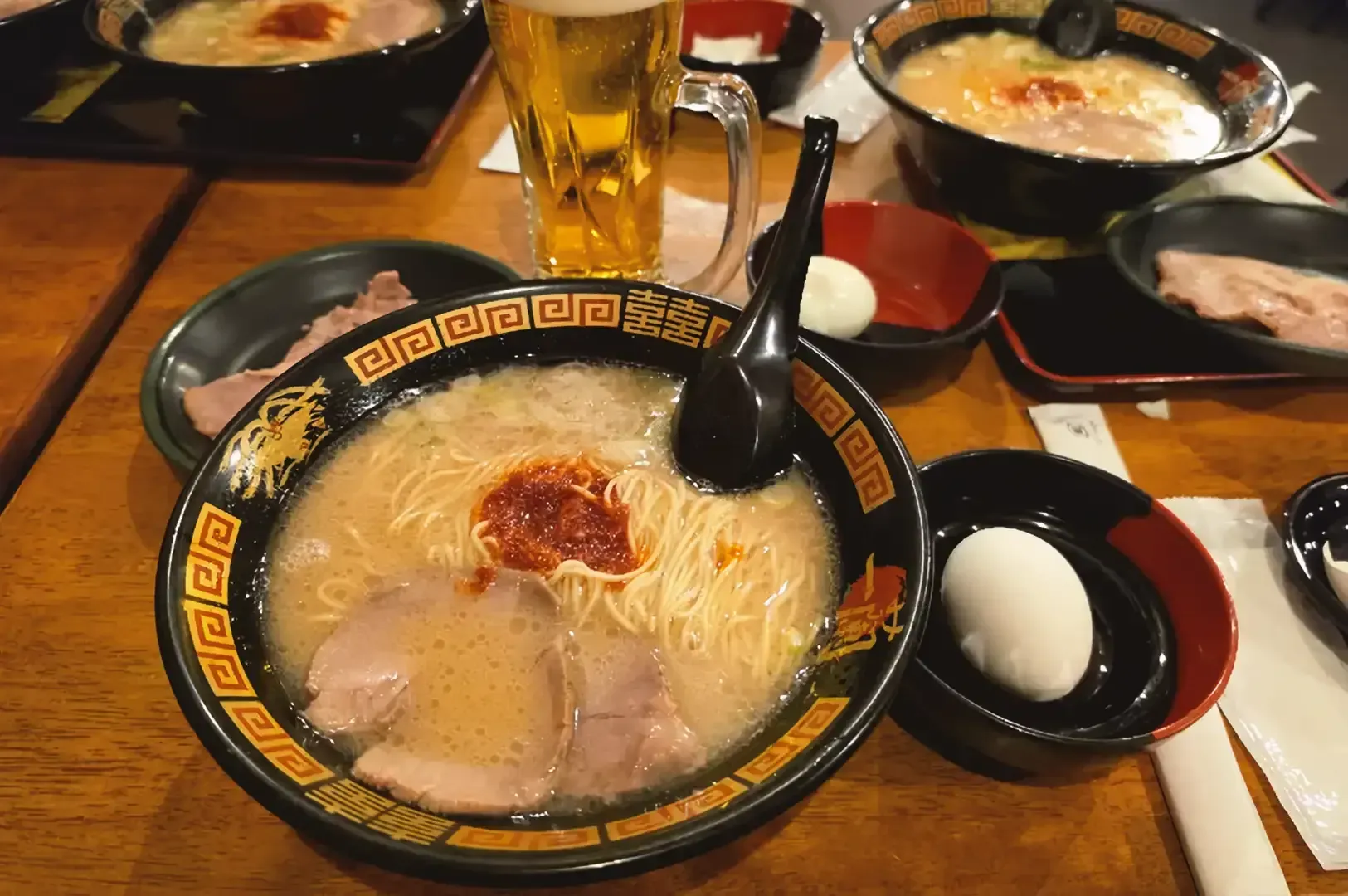 Rich creamy tonkotsu ramen with slices of pork served with egg on a black traditional ramen bowl