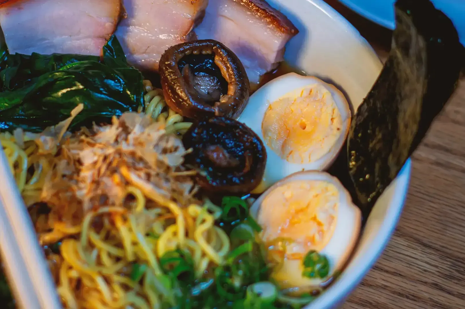 Close up of ramen ingredients composed of shiitake mushroom, egg, noodles, seaweed and chashu