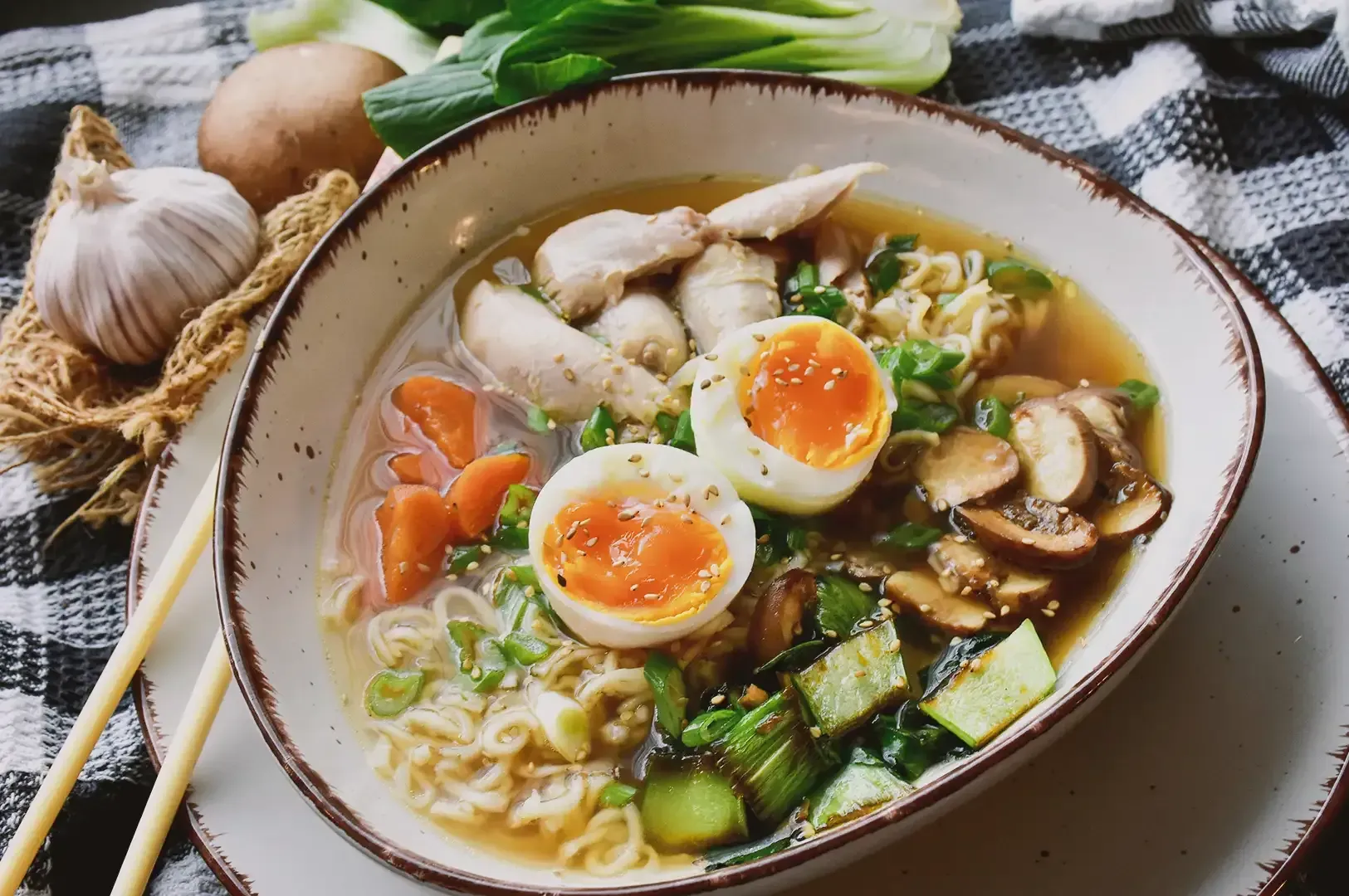 Close up of ramen packed with various vegetables: shiitake mushroom, cabbage carrots, egg and spring onions