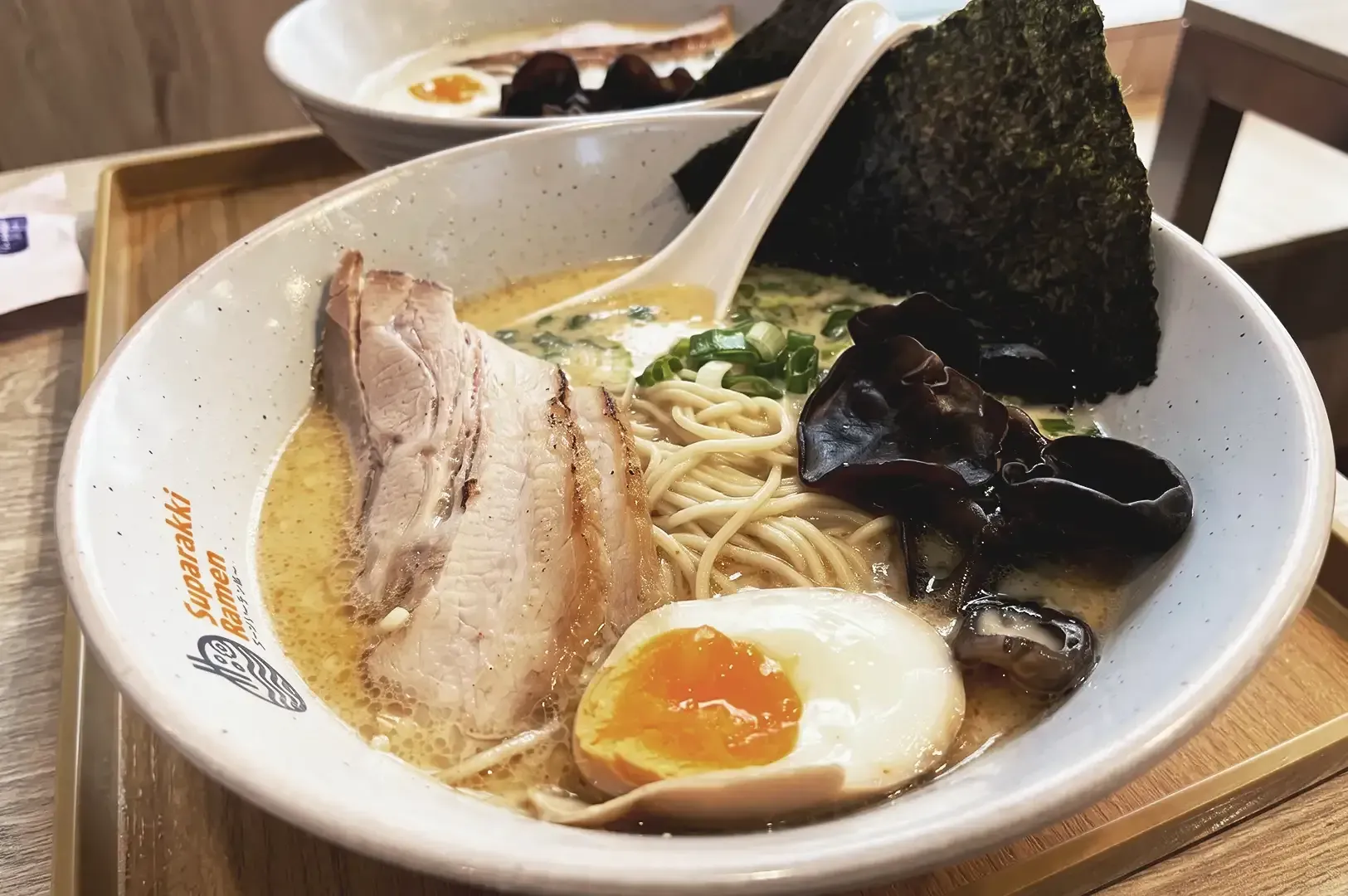 Bowl of Tonkotsu ramen with pork meat, egg, seaweed and black fungus garnished with spring onions