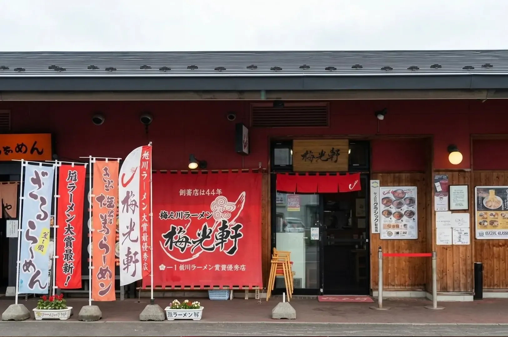 Traditional Japanese ramen restaurant exterior in Asahikawa with red banners displaying Japanese text and restaurant signage