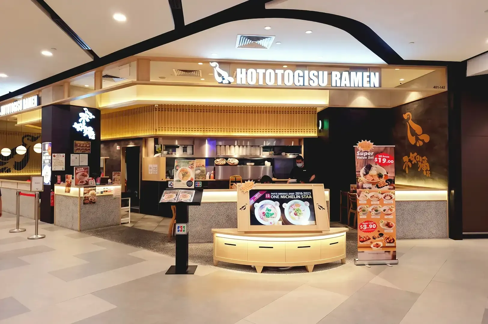 Warm lighted storefront of Konjiki Hototogisu Ramen with visible poster and LED menu displays