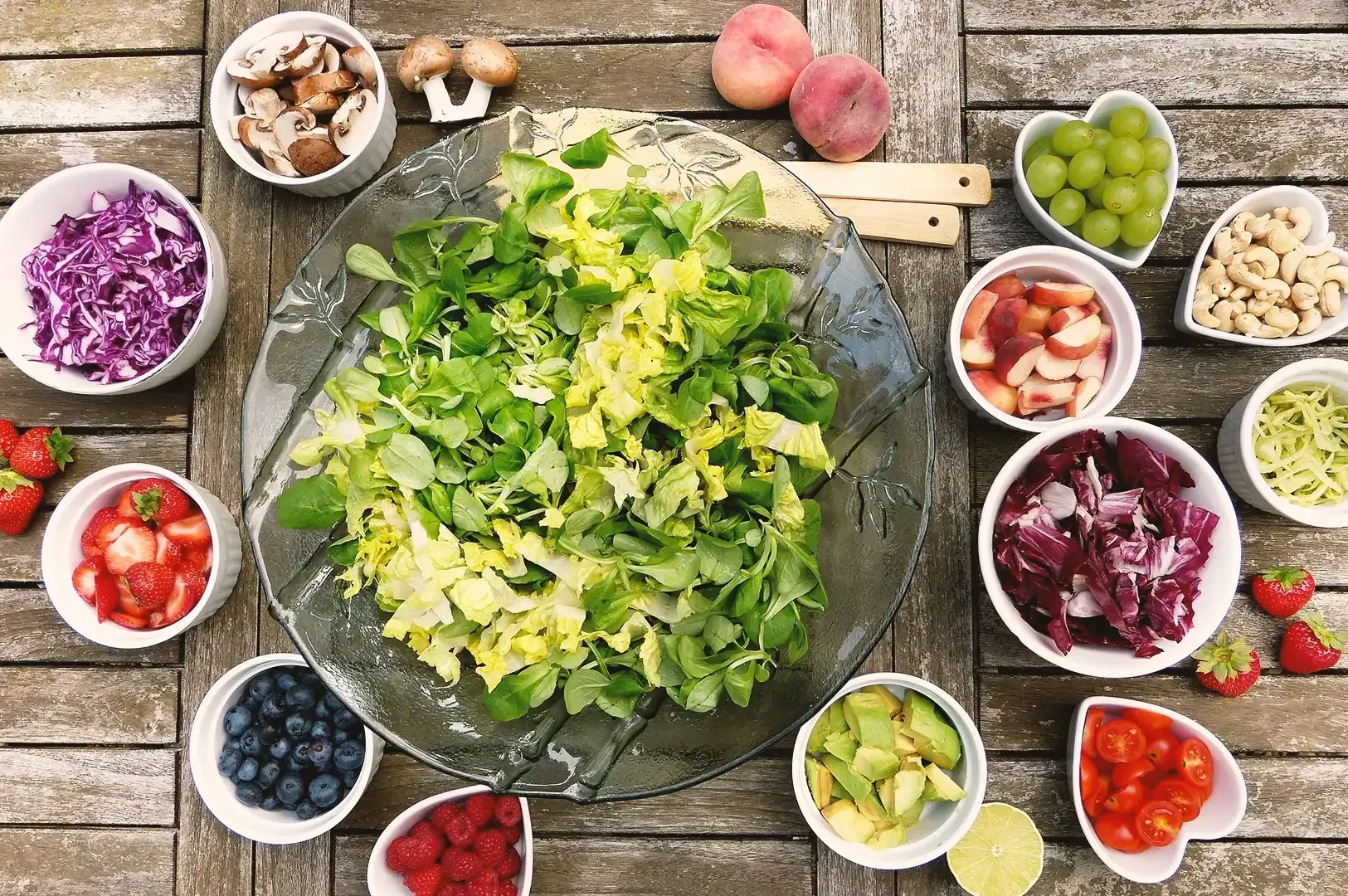 Top view of shredded vegetables and fruits placed in white bowls on a wooden table