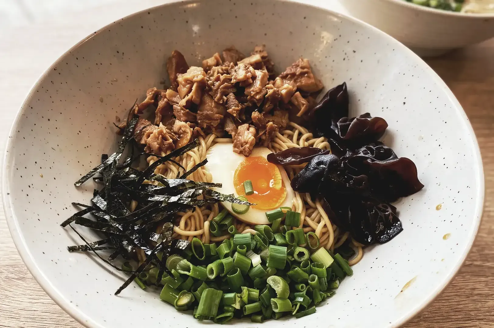 Bowl of ramen with dry truffles, black fungus, egg and shredded seaweeds garnished with spring onions