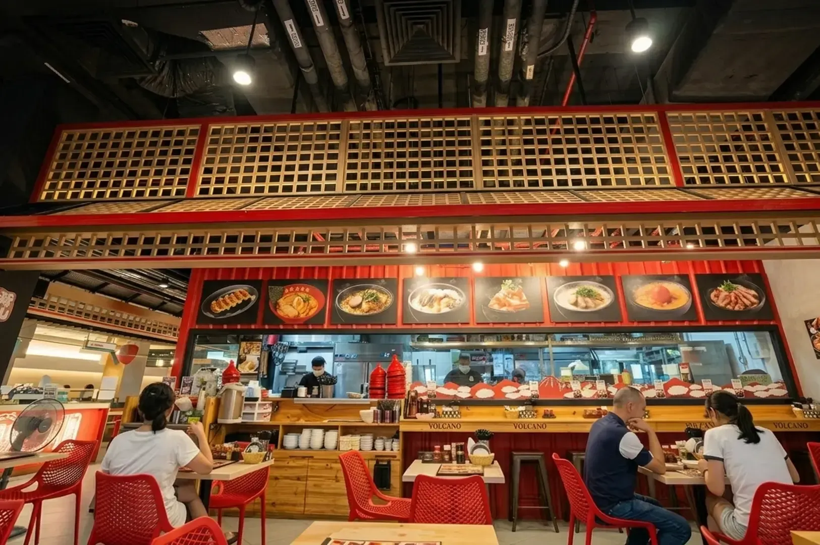 The interior of the ramen restaurant featuring red and gold Japanese-style lattice decor and a busy dining area