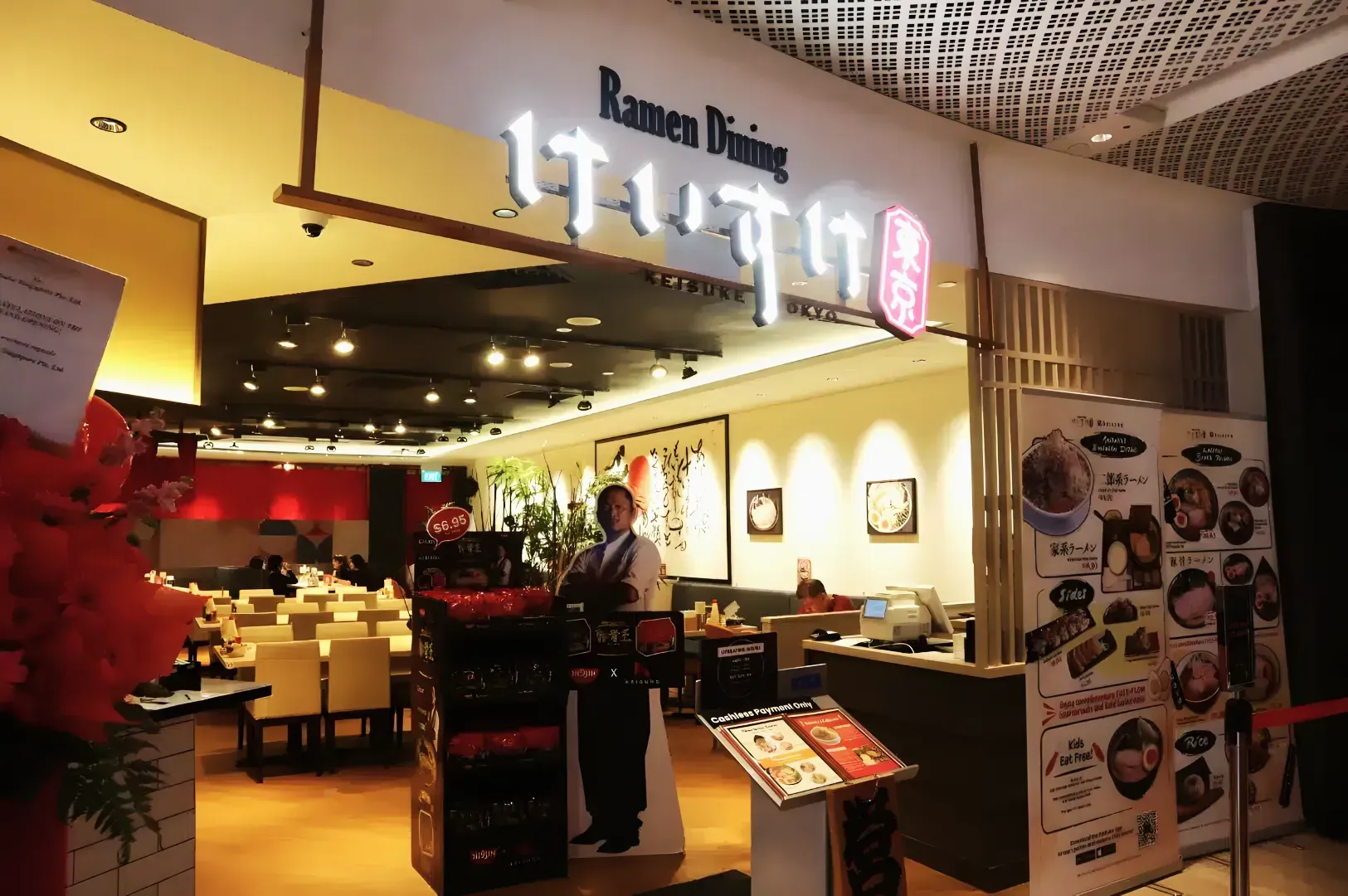 Storefront of Ramen Dining Keisuke Tokyo at Suntec City, featuring the glowing restaurant sign, a menu stand, and a view of the indoor seating area.