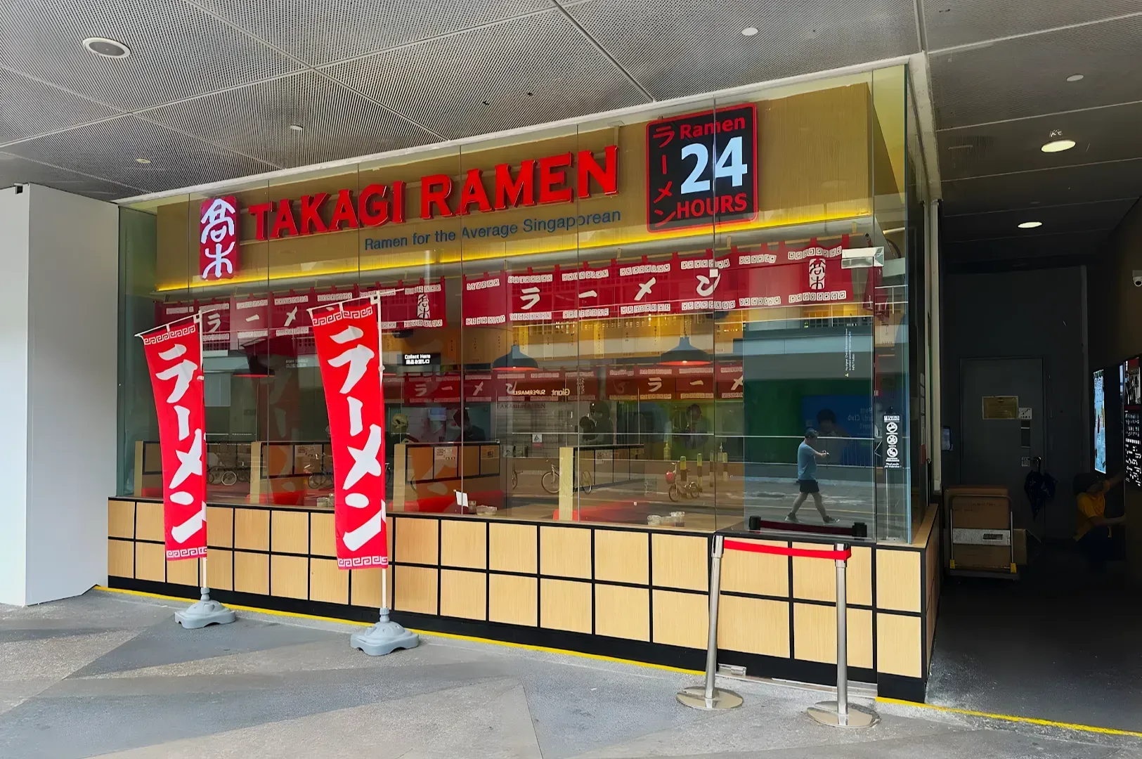 Street view of a ramen shop with large red sign reading