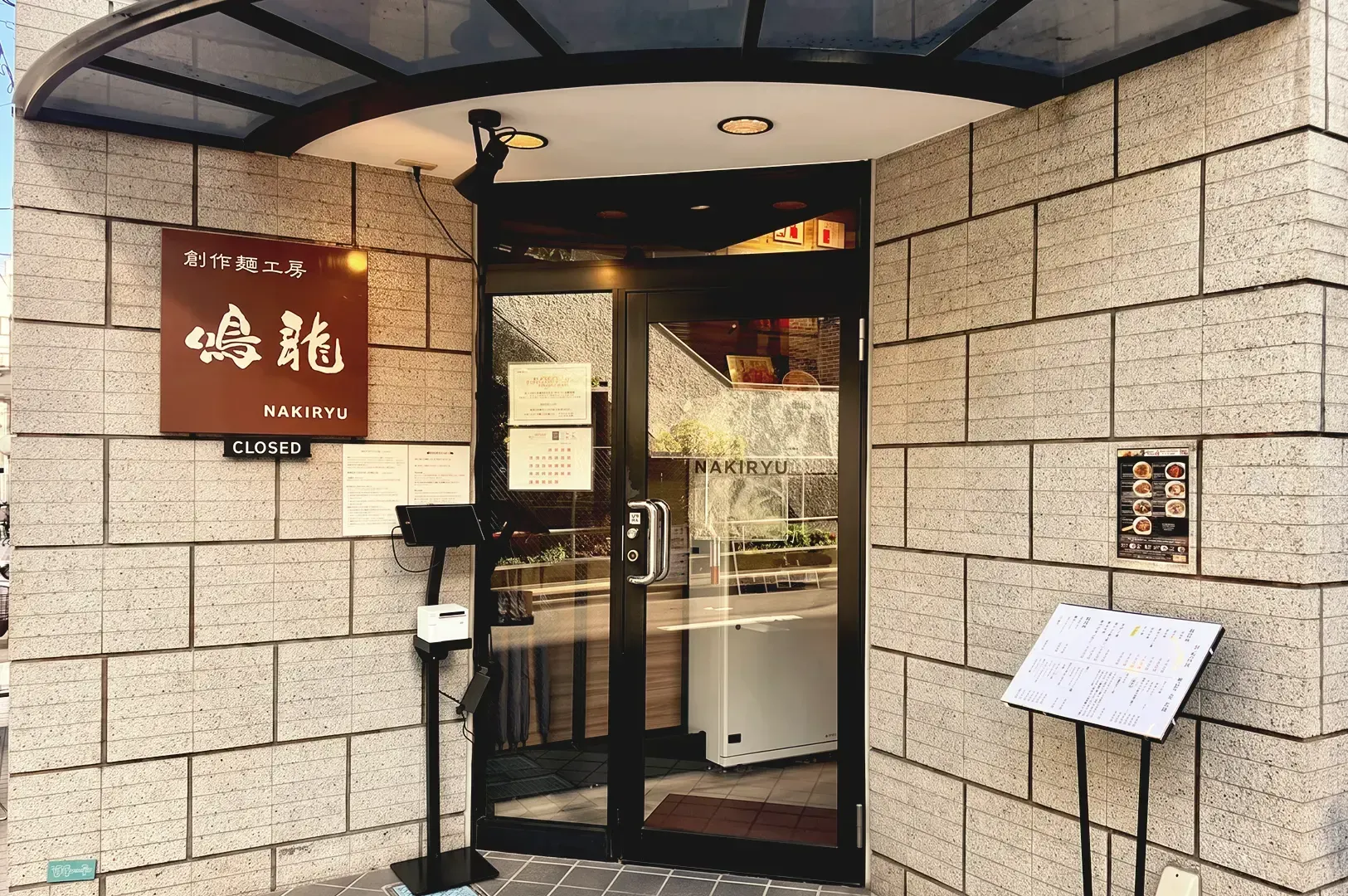Modern brown and beige themed entrance of Nakiryu with brown signage and menu attached to the wall