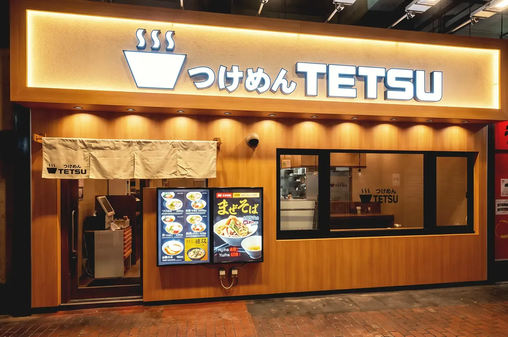 Warm lighted wooden theme storefront of Tetsu with menu displayed beside the entrance