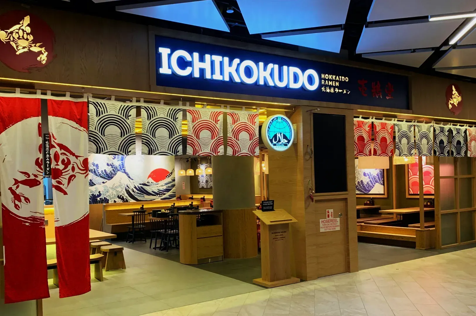 Front view of Ichikokudo Ramen restaurant, with traditional Japanese decor, red and white banners, and Japanese wave art inside. Cozy and inviting.
