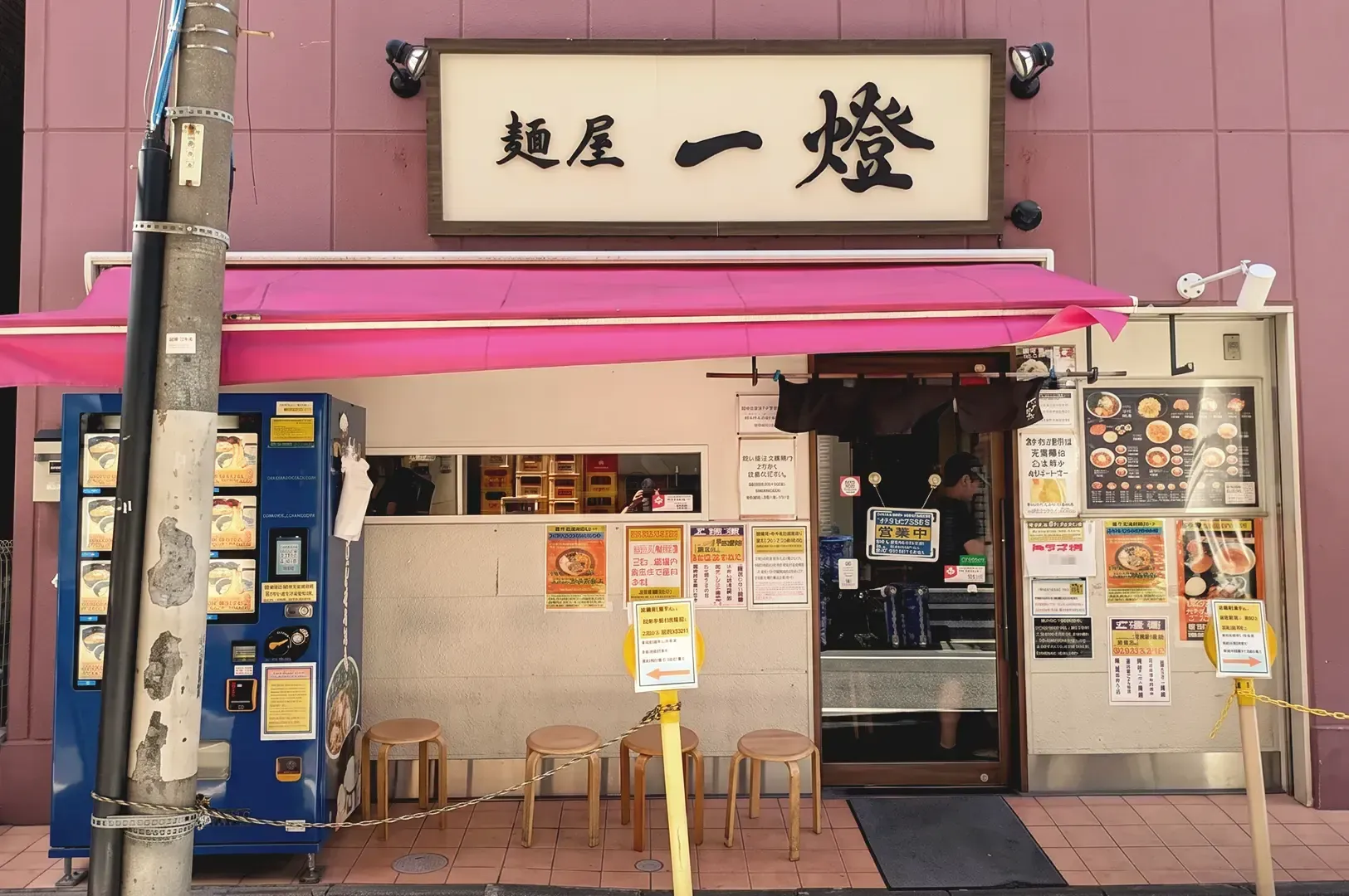 Beige walls with pink roofing decorated with menu posters of Menya Itto